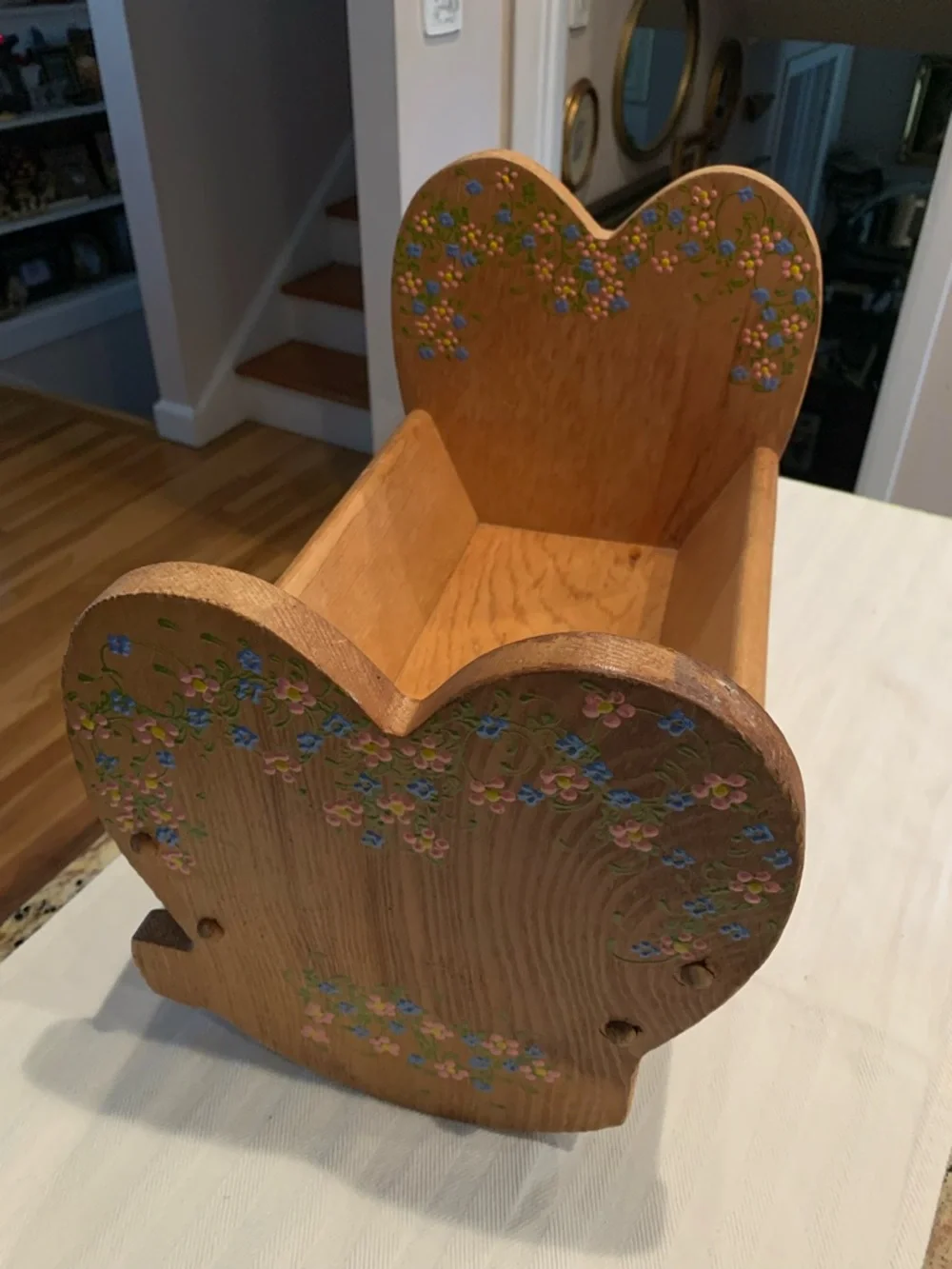 Vintage wooden doll cradle heart-shaped design painted with floral details.